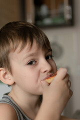 Close-up of a boy with blond hair sitting at the kitchen table and eating a pancake. homemade breakfast