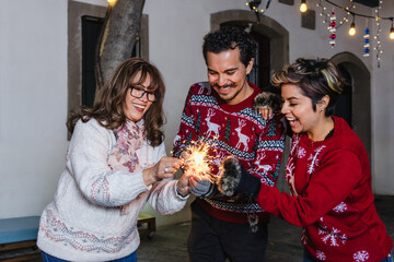 mexcian family celebrating Mexican Posadas holding bengal or sparkling lights in Christmas eve in...