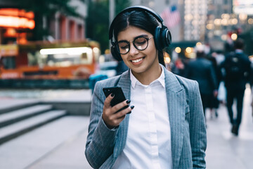 Obraz premium Happy elegant businesswoman walking in downtown and using smartphone