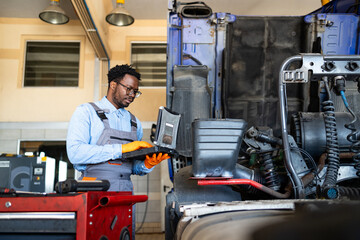 Professional truck repairman using laptop diagnostic tool to service the vehicle.