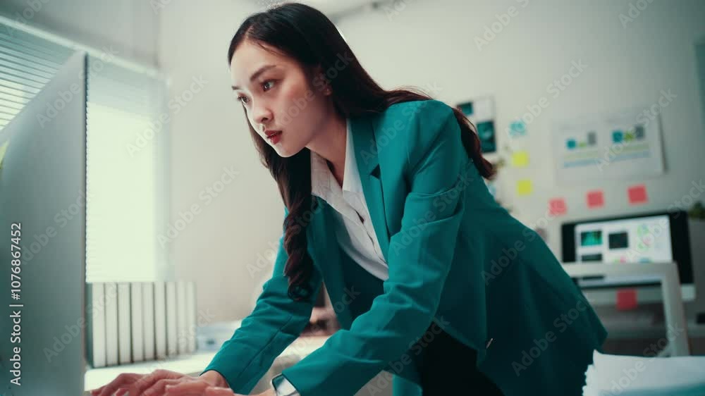 Poster young professional woman in office suit concentrating while typing on computer keyboard. she is lean