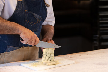 Chef chopping blue cheese for his restaurant recipe. Copy space, close up.