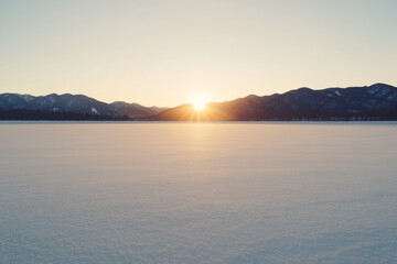 A large, empty field with a bright sun in the sky