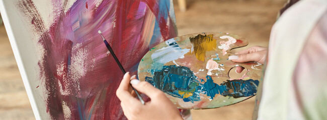 A young woman enjoys expressing her creativity by painting at home, working intently on her artwork.