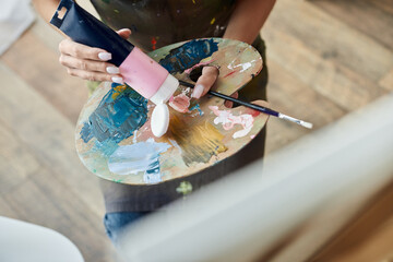 A young woman with natural makeup immerses herself in painting at home, expressing her artistic side.