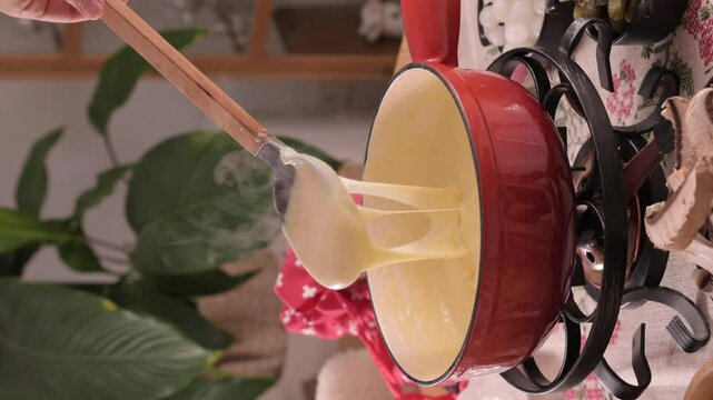 Cozy Swiss fondue setup with melted cheese, bread, pickles, and wine on a rustic table. advertising, social media campaigns, or food-related promotions. High quality 4k footage