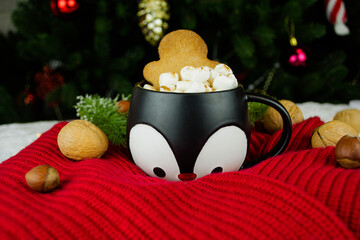 Christmas card with red sweater, nut, mug with hot cocoa with marshmallows and cookies on christmas tree background.