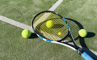 Tennis racket and tennis ball on court.