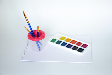 Top view of watercolors in a container and brush. Palette and shades of paint colors. Background with brush and paint for drawing.