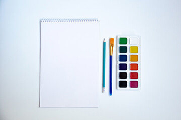 Top view of watercolors in a container and brush. Palette and shades of paint colors. Background with brush and paint for drawing.