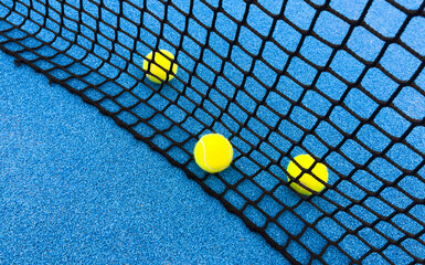  paddle tennis balls near the lines of a blue paddle tennis court, racket sports concept