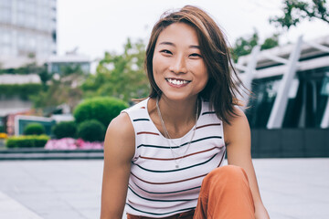 Carefree young woman sitting with gadget on fence