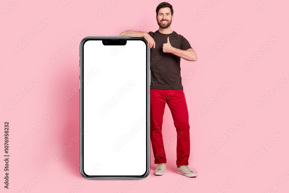Poster Full size photo of satisfied man dressed t-shirt lean on smartphone display empty space show thumb up isolated on pink color background