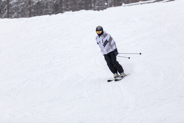 Man Skiing Down a Snowy Slope in the Forest During a Winter Afternoon