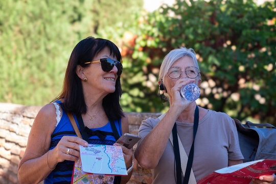 Senior couple of caucasian women traveling in Europe with help of maps and phone indications