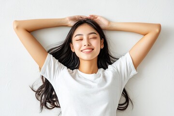 Fototapeta premium Happy young woman relaxing on the floor with arms raised, smiling, bright atmosphere.