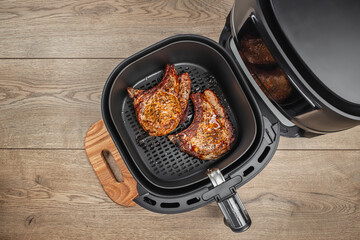 grilled steaks from air fryer oven on a wooden background, easy crispy food with little or no fat by circulating hot air inside the basket