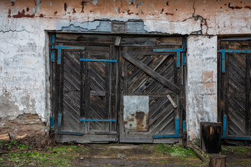 Abandoned wooden gate leads into a decayed building with brick walls