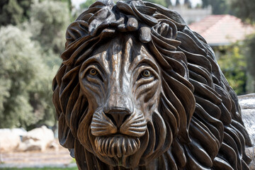 Closeup detail of the textured head and furrowed mane of a bronze lion sculpture in a Jerusalem park.