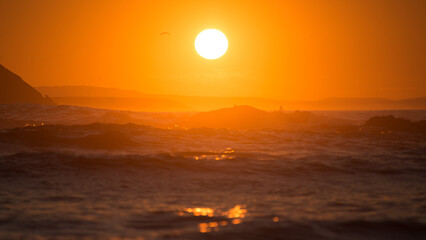 Orange sunset over ocean waves in the back