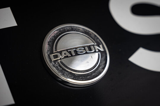 Weathered Datsun badge on a black Datsun 240Z