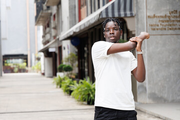 Candid of African man model with dreadlocks hairstyle wearing white t-shirt standing in the city