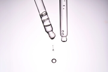Two pipettes with a cosmetic product. Serum or fluid drips from one of them.