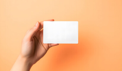 A hand holding a blank white card against a vibrant orange background. The minimalist design allows for customizable text, logos, or other branding elements, ideal for business or promotional use.