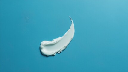Thick small patch of conditioner in swoosh shape on blue solid background.