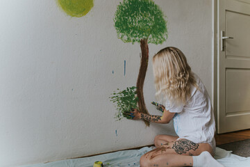 Woman Engaged in Wall Painting, Creating a Tree with Hands