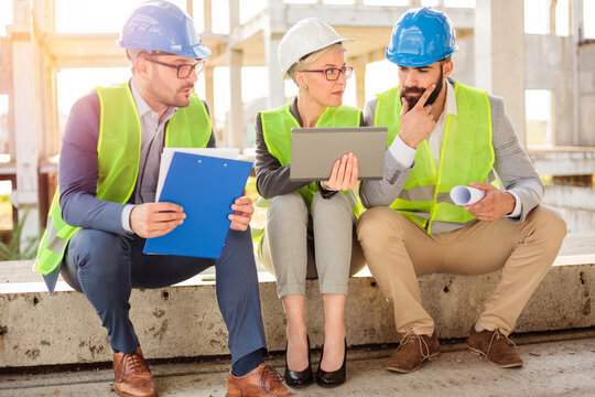Team of successful young architects and business partners having a meeting on a construction site. Discussing project details