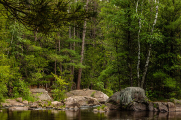 The rocky, boulder shoreline of the Pike River just above the upper falls at Dave's Falls Marinette County Park, Amberg, Wisconsin in late June