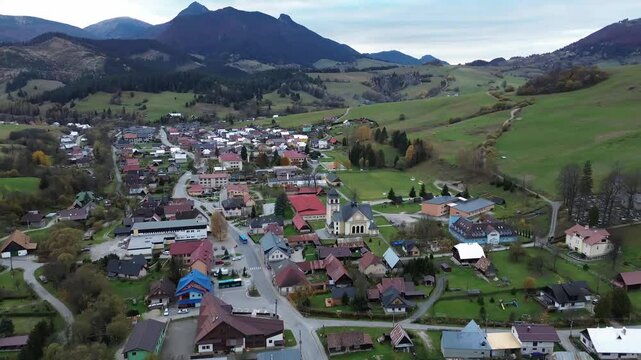 Aerial drone view of nature in the Carpathians in Romania at sunset. Village located in a valley, hills covered with lush forest