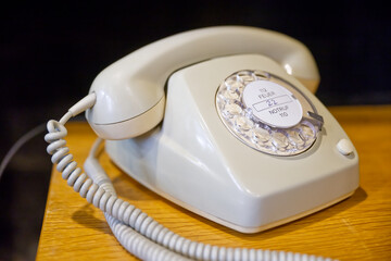Ein weiß beige farbenes altes Wählscheiben-Telefon hat noch ein unberührtes Telefonnummernschild...