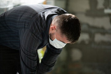 A man in a mask performs repair work on the background of a block wall.