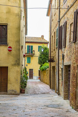 Narrow street with old houses in Tuscan city Pienza, Italy