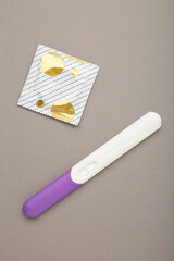 Pregnancy test and condom on grey background. Vertical photo