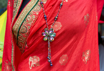 Red Indian saree with gold embroidery and glass flower pendant.