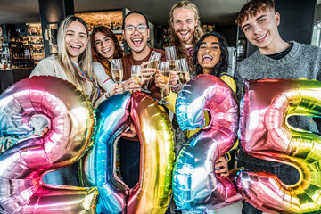 Happy group of friends cheering champagne wine and celebrating new 2025 year at bar restaurant -...