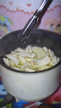 beautiful vertical video portrait cooking thinly sliced ​​meatballs fried in an electric fryer and basreng is a typical Indonesian snack