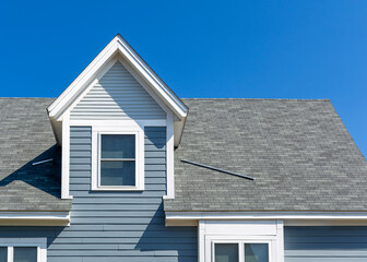 Gable dormer with blue-gray clapboard siding and white trim on family house in Brighton, Massachusetts, USA
