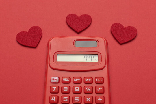 Red Calculator with Heart Symbols on Red Background - Love and Finance Concept