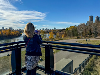Edmonton, Alberta - October 13, 2024: A woman taking pictures of the views of the Edmonton skyline...