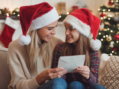 Madre e hija con gorros de Pap&aacute; Noel leyendo una carta
