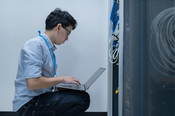 Fototapeta premium Computer engineer is setting up network in server room,Systems Maintenance Technician,Male engineer working in server room at modern data center