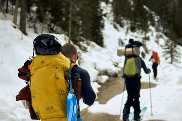 Hikers traverse a snow-covered trail in a mountainous region during winter