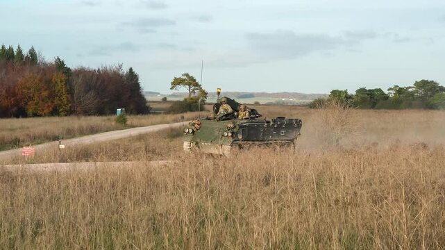 Commander directing a British army Bulldog FV432  armoured personnel carrier tank driving along a dirt track 