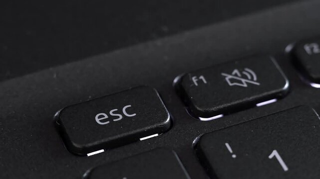 Close up view of finger pressing laptop ESC button, notebook keyboard. Concept of quitting software, interruption, abort, sign of problem or cyber attack, quit online office work, stop input data.