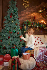 Cute little girl hanging ornaments and balls on Christmas tree. Kid decorating Christmas tree.