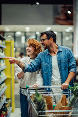 Happy couple choosing groceries, enjoying shopping together in supermarket